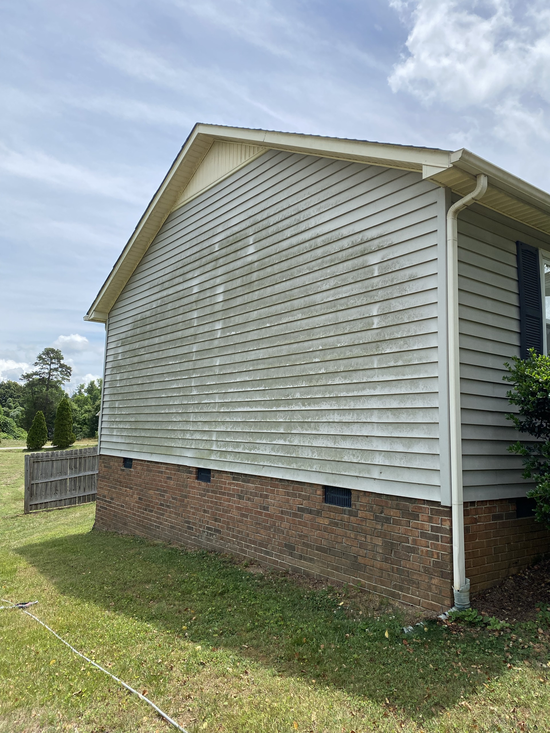 House siding before cleaning, with visible green mildew buildup